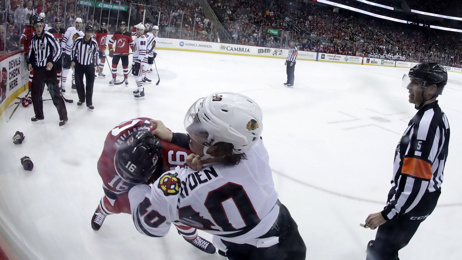 New Jersey Devils defenseman Steven Santini (16) and Chicago Blackhawks right wing John Hayden (40) fight during the first period of an NHL hockey game, Saturday, Dec. 23, 2017, in Newark, N.J. (AP Ph ...