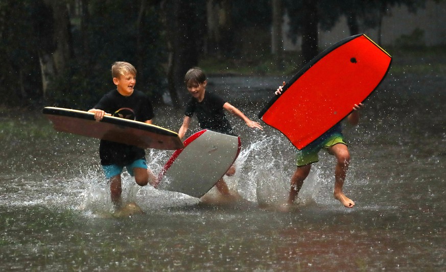 epaselect epa09788397 Kids play in the wet at Chinderah, NSW, Australia, 27 February 2022. With the death toll from floods in Queensland and NSW rising to six, severe weather warnings remain in place  ...