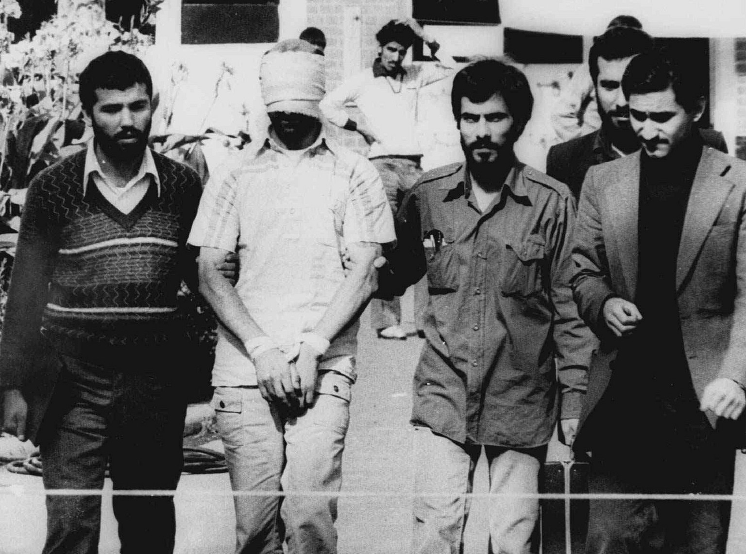 In this Nov. 9, 1979 photo, one of the hostages being held at the U.S. Embassy in Tehran is displayed blindfolded and with his hands bound to the crowd outside the embassy. Fifty-two of the hostages e ...