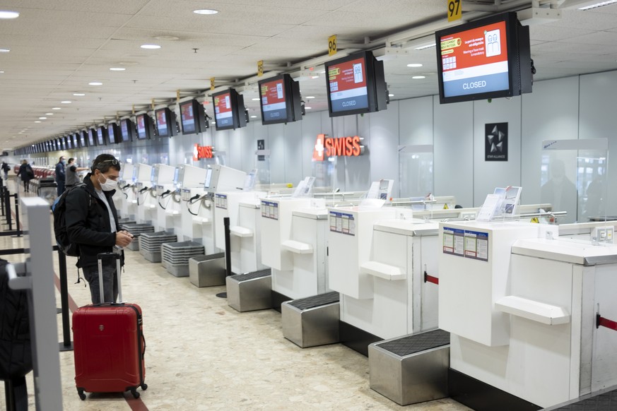 epa08813676 Passenger wearing a face mask waits for check-in at the counter of the Swiss International Air Lines at the Geneva Airport (Geneve Aeroport) during the coronavirus disease (COVID-19) outbr ...