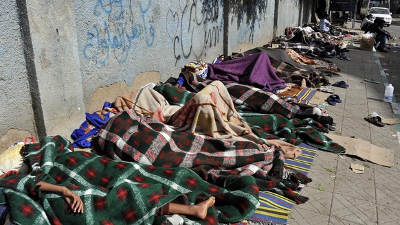 epa04190193 Eritrean refugees sleep on the sidewalk of a street as they wait for help from UNHCR in Sana'a, Yemen, 03 May 2014. Reports state over 210 Eritrean refugees, including women and children, called on the UN Refugee Agency to provide them with protection and assistance, especially most of them allegedly having fled from Eritrea to Yemen to avoid forced military service. EPA / YAHYA ARHAB