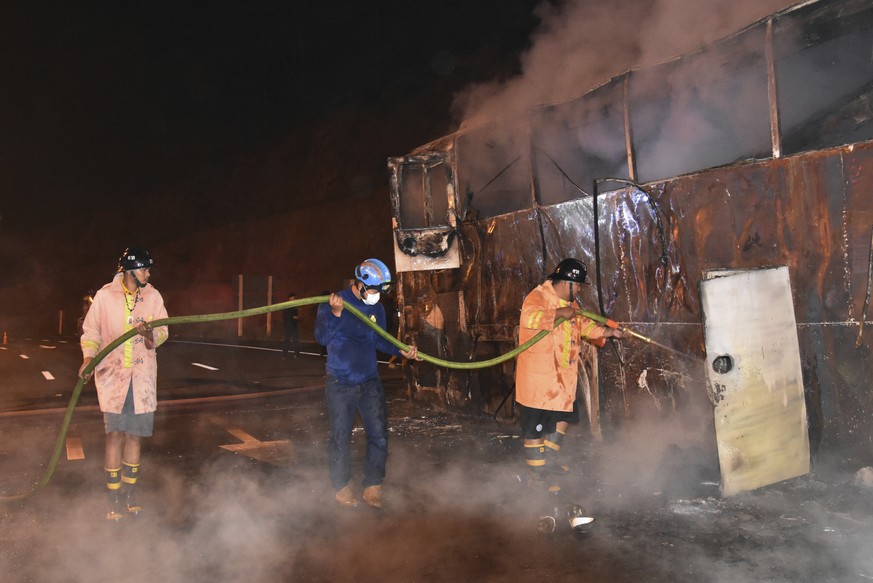 Thai firefighters work on a burnt double-decker bus in Tak province, Thailand, Friday, March 30, 2018. Police say a fire on a bus carrying migrant workers to Thai factories has killed 20 people. It oc ...