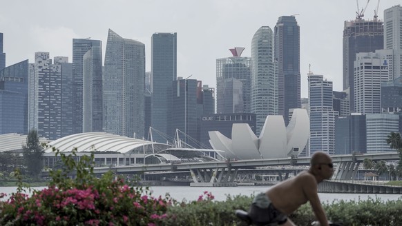 epa09013609 A cyclist rides past the skyline of the financial district in Singapore, 15 February 2021. Singapore has reported a 5.4 percent contraction in its economy in 2020, above advanced estimates ...