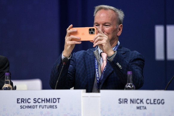 epa10954759 Eric Schmidt, co-founder of Schmidt Futures, uses his smartphone ahead of a plenary session on day two of the AI Safety Summit 2023 at Bletchley Park, Milton Keynes, Britain, 02 November 2 ...
