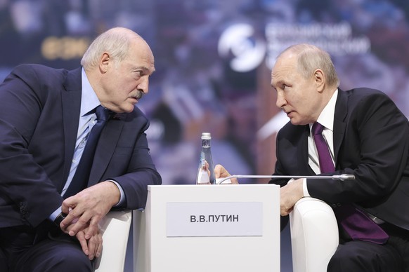 In this photo released by Roscongress Foundation, Russian President Vladimir Putin, right, and Belarusian President Alexander Lukashenko talk to each other during the plenary session of the Eurasian E ...