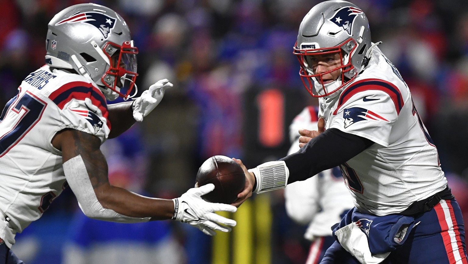 New England Patriots quarterback Mac Jones, left, hands off to cornerback J.C. Jackson during the first half of an NFL football game against the Buffalo Bills in Orchard Park, N.Y., Monday, Dec. 6, 20 ...