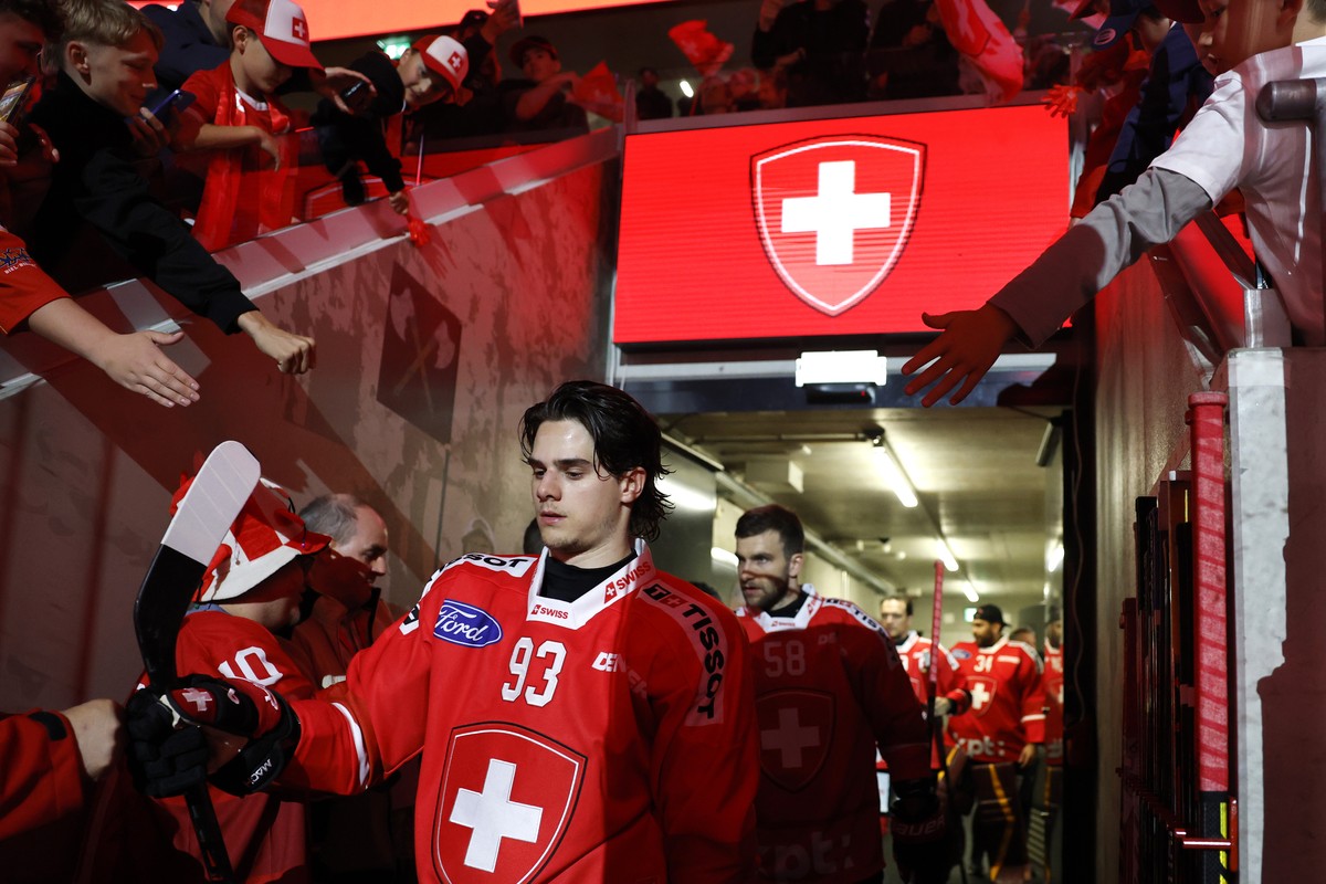 Swiss fans cheer as Theo Rochette, front, Simon Le Coultre, back, and their teammates walk out of the locker room, prior to a friendly ice hockey match between Switzerland and Hungary, Thursday, April ...