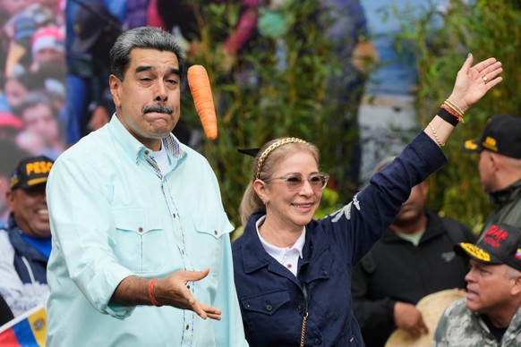 President Nicolas Maduro tosses a carrot next to his wife Cilia Flores during a rally marking the anniversary of the Battle of Santa Ines, which took place during Venezuela's 19th-century Federal ...