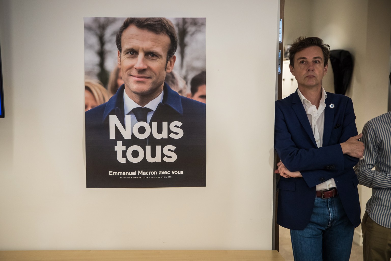 epa10022911 A poster of French President Emmanuel Macron displayed as journalists and supporters attends an electoral party for the results of the second round of the French legislatives elections, at ...