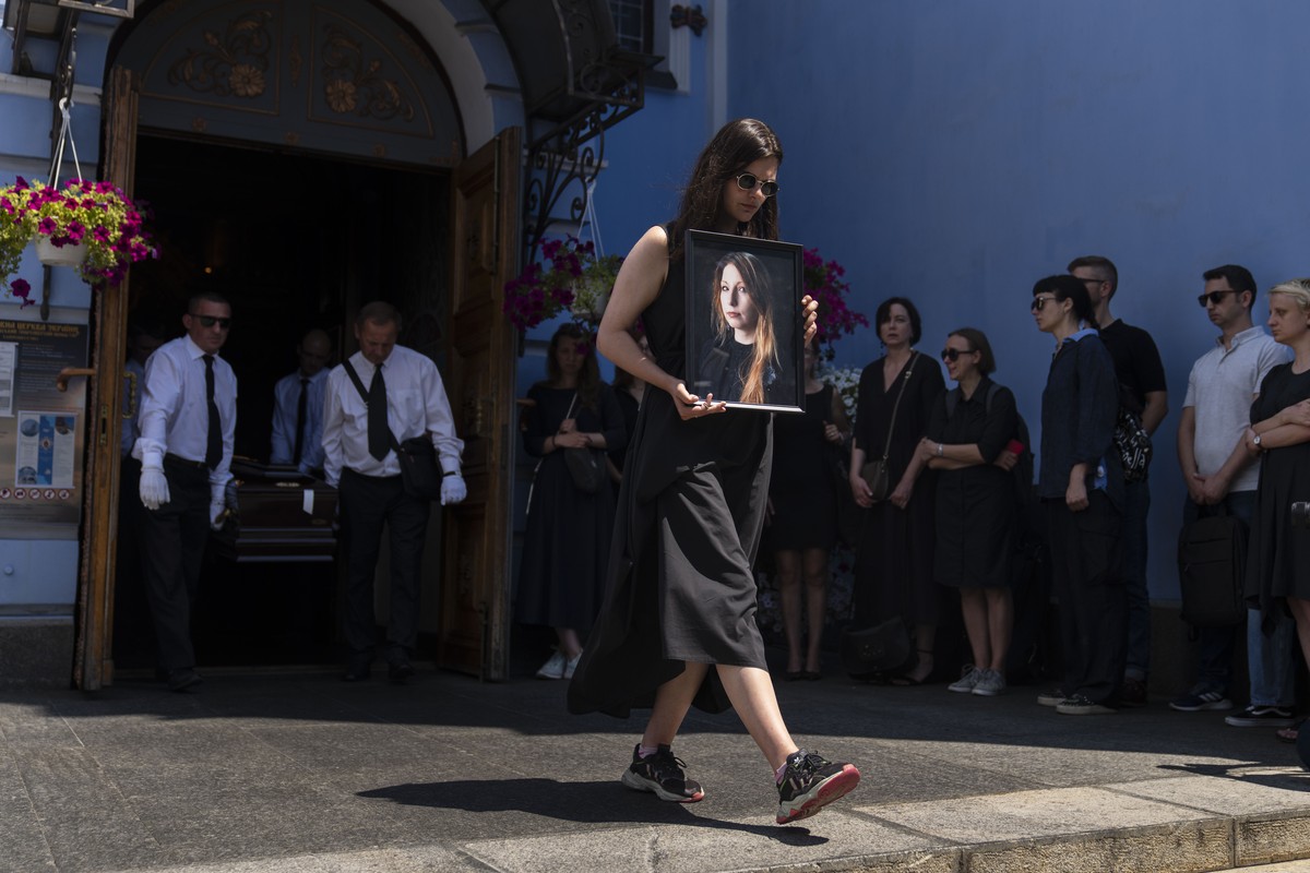 Sofia Cheliak carries a photo of Ukrainian writer Victoria Amelina as she and pallbearers walk toward a hearse after a memorial service for Amelina at St. Michael's Golden-Domed Monastery in Kyiv ...