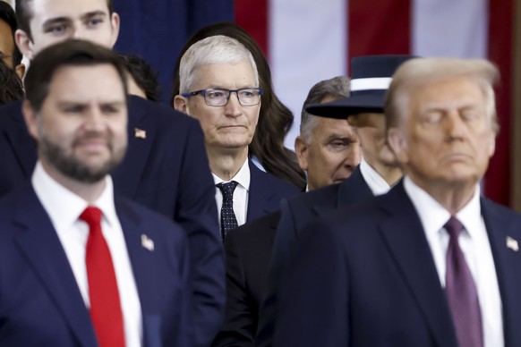 epa11839408 Apple CEO Tim Cook (C) seen behind US President Donald Trump (R) and US Vice President JD Vance (L) after the two were sworn into office at an inauguration ceremony in the rotunda of the U ...