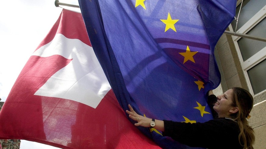 Eine Angestellte des Zuercher Hotels Sheraton entheddert am Montag, den 22. Mai 2000, die Flaggen der Schweiz und der Europaeischen Union (EU), nachdem sie sich aufgrund des starken Windes ineineander ...