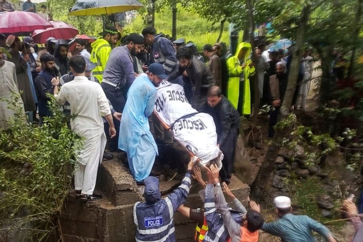In this photo released by Rescue 1122 Emergency Department, rescue workers and local residents recover a body from the site of flash flood incident in a village of Battagram district, Khyber Pakhtunkh ...