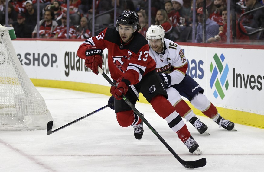 New Jersey Devils center Nico Hischier (13) clears the puck in front of Florida Panthers center Aleksander Barkov during the second period of an NHL hockey game Tuesday, Nov. 9, 2021, in Newark, N.J.  ...