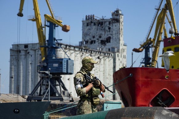 FILE - A Russian soldier guards a pier with the grain storage in the background at an area of the Mariupol Sea Port which has recently started its work after heavy fighting in Mariupol, on the territo ...