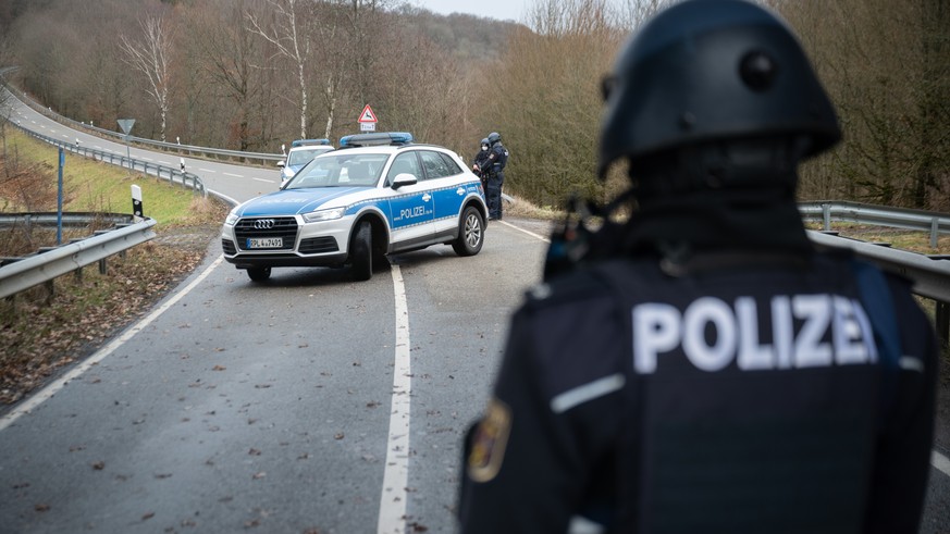 31.01.2022, Rheinland-Pfalz, Mayweilerhof: Polizeibeamte stehen an einer Absperrung an der Kreisstra