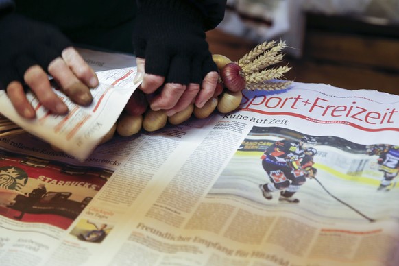 Eine Verkaeuferin packt Zwiebeln in eine alte Ausgabe der Berner Zeitung, waehrend dem traditionellen &quot;Zibelemaerit&quot; am Montag, 23. November 2015 in Bern. Der Zibelemaerit findet am vierten  ...