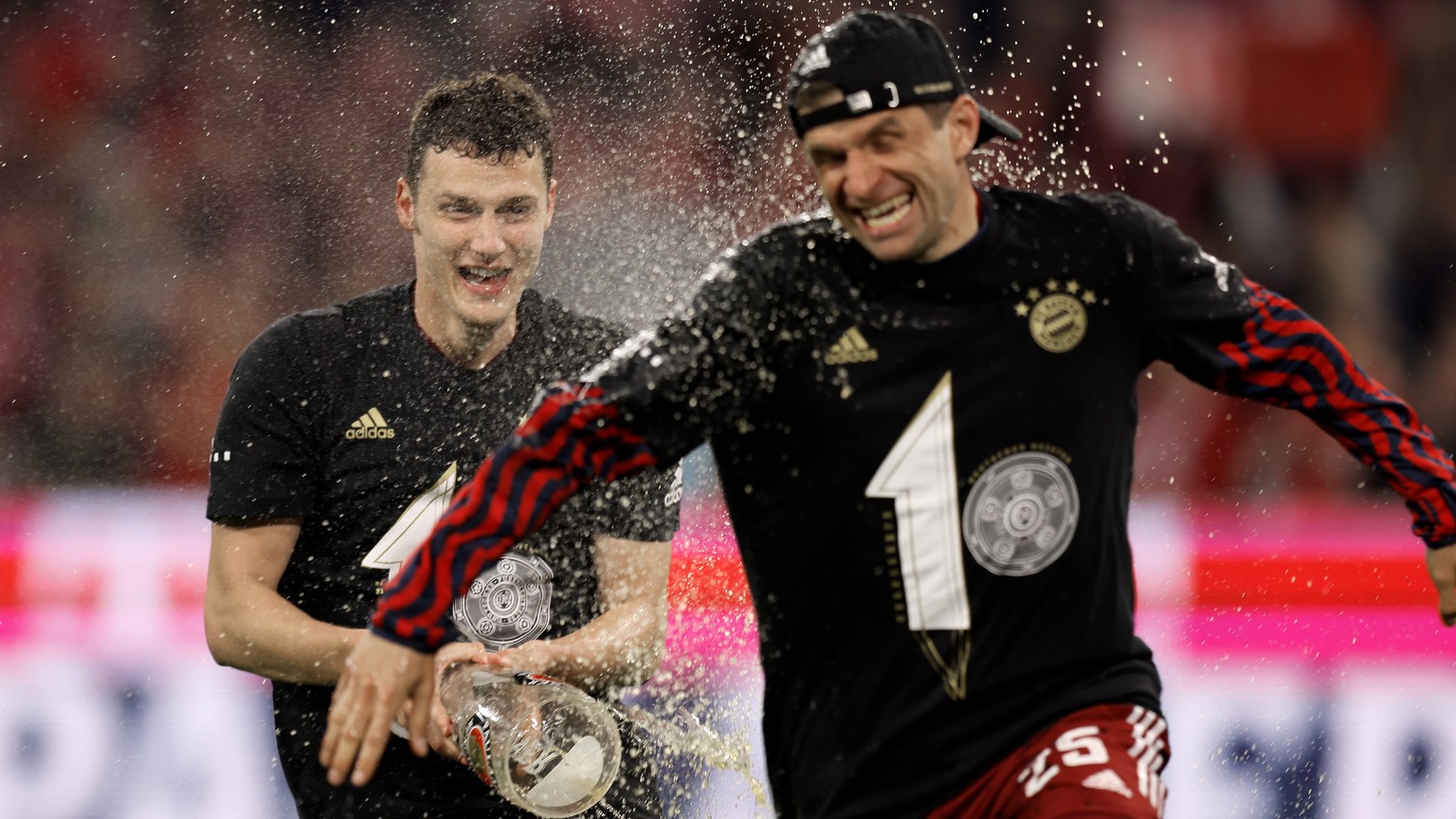 epa09904957 Bayern&#039;s Benjamin Pavard (L) and Thomas Mueller (R) celebrate the tenth consecutive Bundesliga title, after winning the German Bundesliga soccer match between FC Bayern Muenchen and B ...