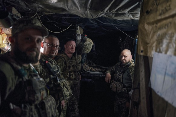 Ukrainian soldiers of the 28th brigade stand together in a shelter on their position close to Bakhmut, Donetsk region, Ukraine, Monday, March 27, 2023. (AP Photo/Libkos)