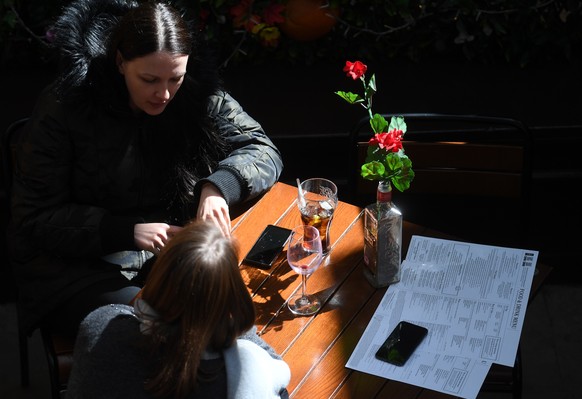 epa09130907 People sit in an outside cafe in London, Britain, 12 April 2021. From 12 April 2021, pubs and restaurants serving outside can reopen along with non-essential shops, gyms and hairdressers,  ...