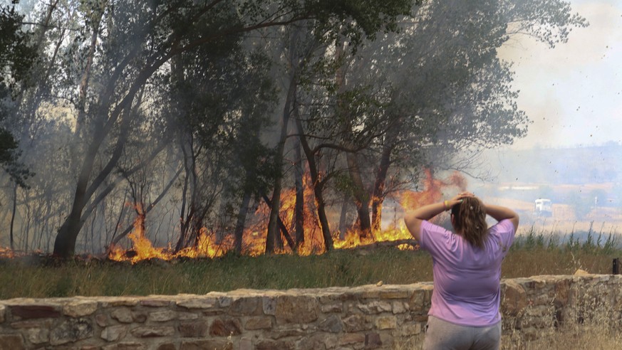 epa10077470 A woman reacts as she watches the flames of a fire in the village of San Martin de Tabara (Zamora), Spain, July 18, 2022. The heat wave sweeping across Spain is fueling wildfires in fi...