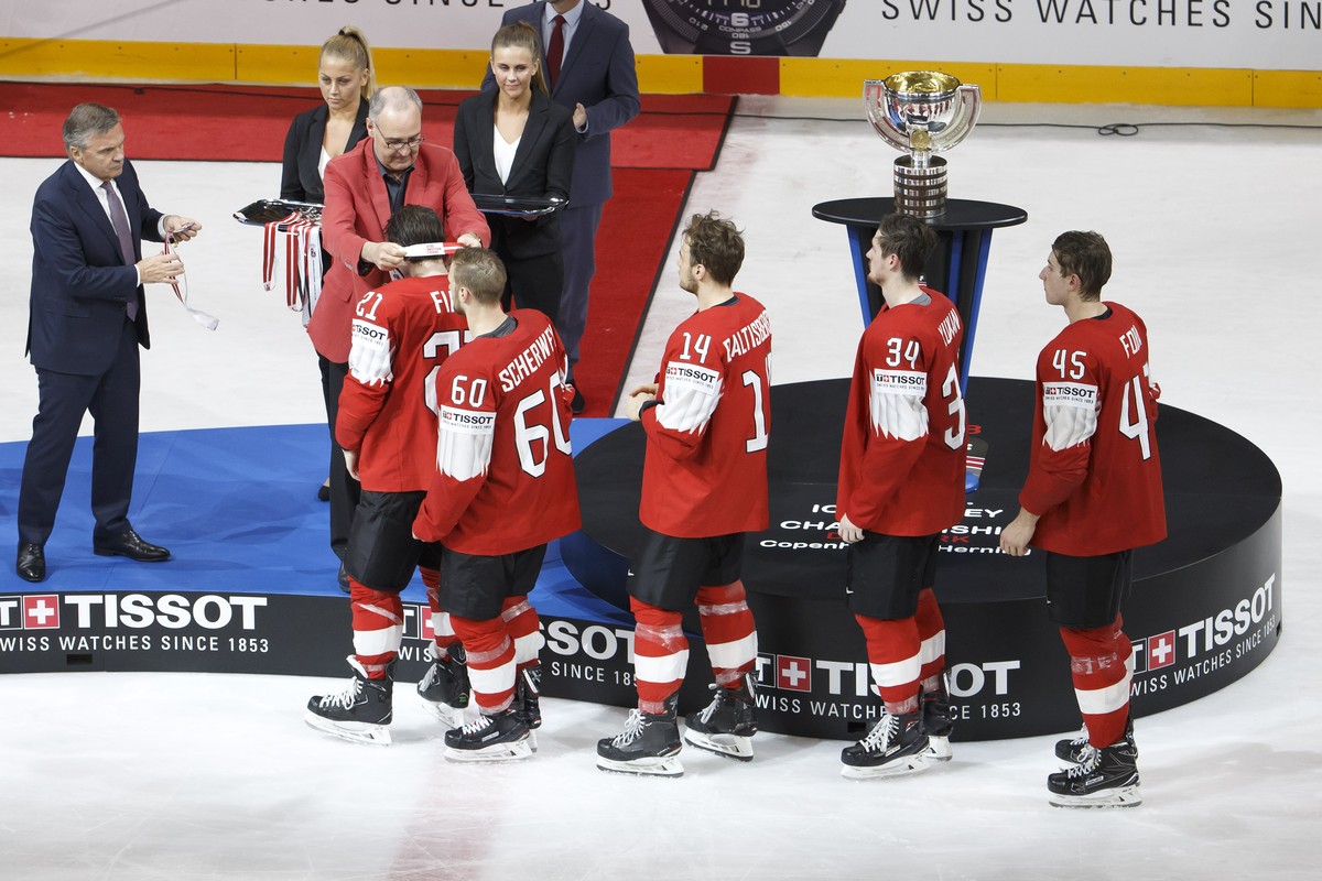 Swiss Defense and Sport Minister Guy Parmelin, 2nd left, next to Rene Fasel, left, President of IIHF, gives the silver medal to Switzerland's forward Kevin Fiala past #21 teammates forward Trista ...
