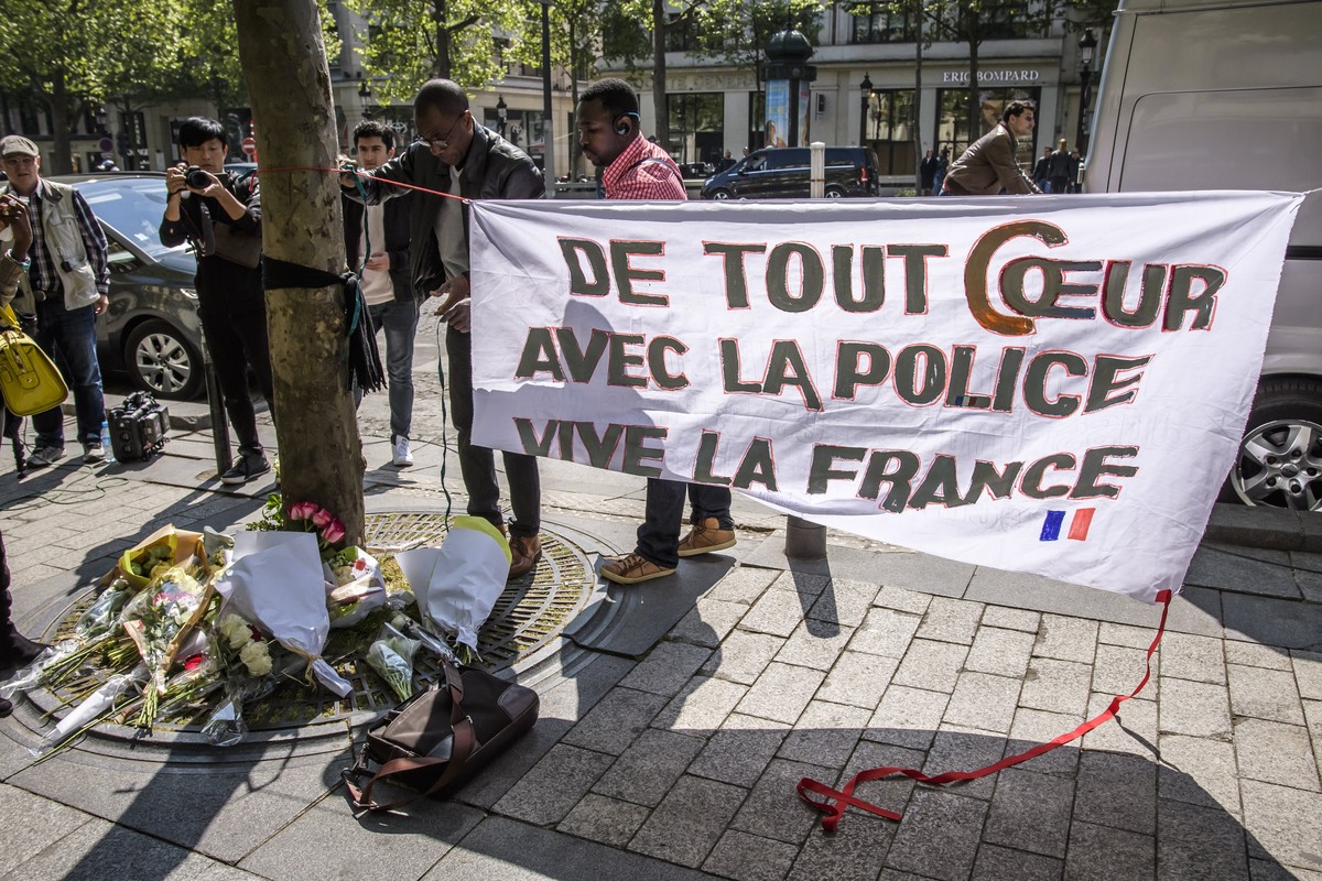 epa05919233 People pay tribute, in front of a banner reading, 'With all my heart with the police, Long live France,' to the French policeman killed at the Champs Elysee avenue in Paris, 21 A ...