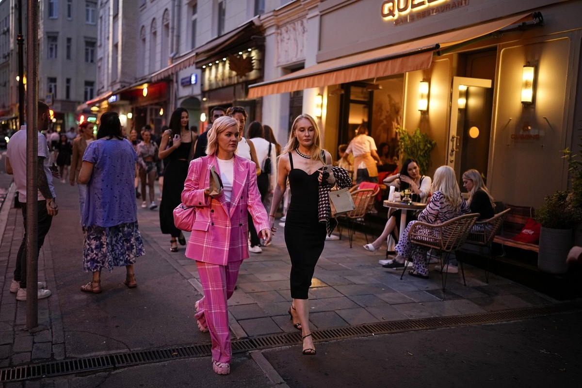 People walk along a street as others sit at a restaurant at Patriarshiye Prudy, which means Patriarch's Ponds, a hip restaurant and bar district enjoying the end of a sunny day in Moscow, Russia, ...