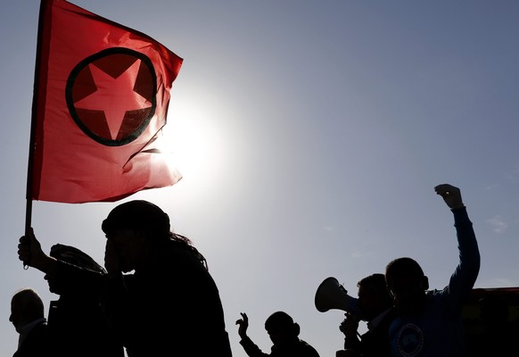 epa04459611 A Kurd carries the flag of the Kurdish Kurdistan Workers&#039; Party (PKK) during the funeral for female Kurdish fighters, killed in clashes against the group calling itself the Islamic St ...