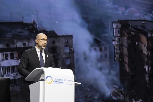 epa10051464 A handout photo made available by Swiss federal Foreign ministry FDFA shows Ukrainian Prime Minister Denys Shmyhal speaks with footage from the war projected on screen during a plenary ses ...