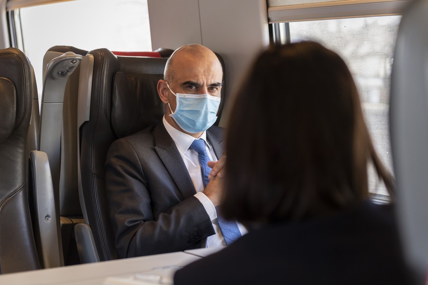 Bundesrat Alain Berset, links, diskutiert mit einer Mitarbeiterin im Zug nach nach Visp, am Montag, 11. Januar 2021 in Bern. Alain Berset wird mit einer Delegation das Schweizer Pharma und Biotech Unt ...