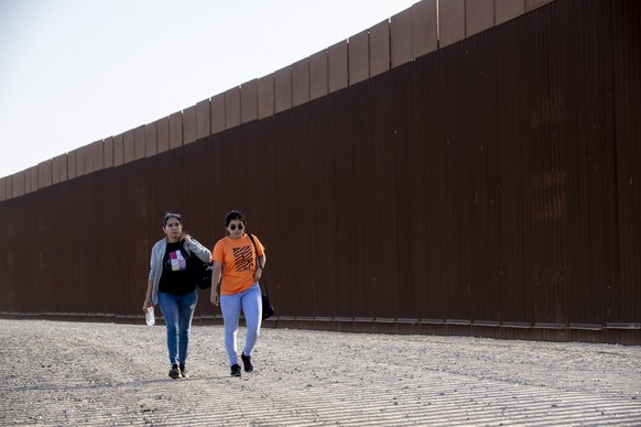epa10623448 Natalia and Matilde (L) walk along the border wall after crossing the border between Mexico and the US illegally, in Yuma, Arizona, USA, 12 May 2023. US Secretary of Homeland Security Alej ...