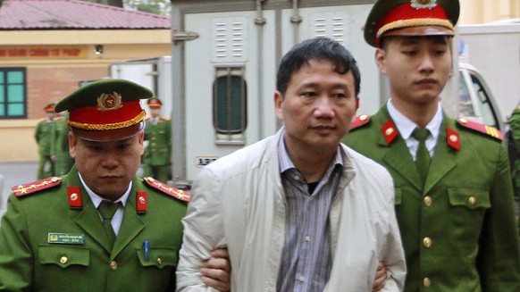 Trinh Xuan Thanh, center, is led to a court room by police in Hanoi, Vietnam, Monday, Jan. 22, 2018. The former oil executive was sentenced to life in prison on charges of embezzlement and mismanageme ...
