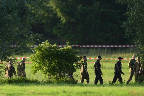 epa07671243 Policemen and soldiers walk in a row near the crash site of a Eurofighter Typhoon fighting jet near the village Nossentin in the area of Waren (Mueritz) in Mecklenburg-Western Pomerania, G ...