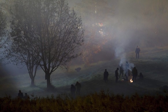 Die Zahl von Asylsuchenden, die auf der Balkan-Route nach Zentraleuropa reisen, nahm in den letzten Tagen merklich ab – Flüchtlinge an der slowenischen Grenze wärmen sich an einem Lagerfeuer.