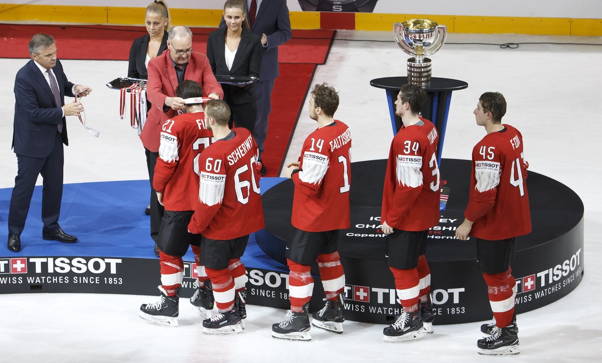 epa06753310 Swiss Defense and Sport Minister Guy Parmelin, 2nd left, next to Rene Fasel, left, President of IIHF, gives the silver medal to Switzerland's forward Kevin Fiala past #21 teammates fo ...