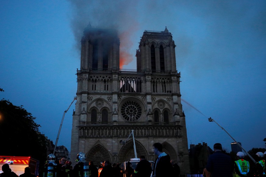 epa07508845 Paris Fire brigade members spray water onto the facade of the Notre Dame Cathedral during the visit by French President Emmanuel Macron (not pictured) in Paris, France, 15 April 2019. A fi ...