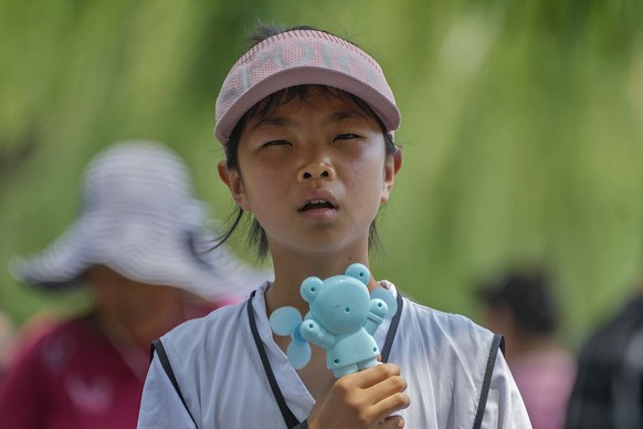 FILE - A child holds an electric fan as they react to the heat during a visit to the Forbidden City in Beijing, July 8, 2024. (AP Photo/Andy Wong, File)