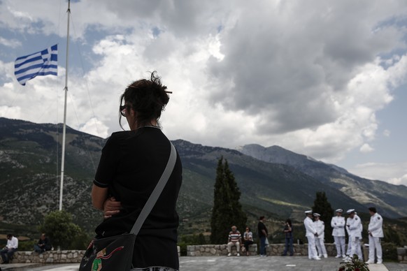 A woman and Greek military officers attend a memorial ceremony outside a mausoleum with the remains of the victims of a massacre at Distomo village about 160km (100 miles) northwest of Athens, Greece, ...