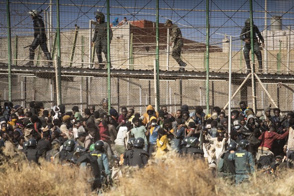 FILE - Riot police officers cordon off the area after migrants arrive on Spanish soil and crossing the fences separating the Spanish enclave of Melilla from Morocco in Melilla, Spain, Friday, June 24, ...