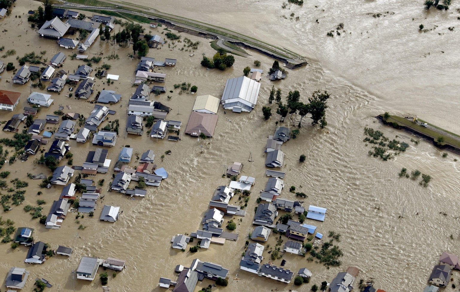 Residential area, center, are submerged in muddy waters after an embankment of the Chikuma River, top right, broke because of Typhoon Hagibis, in Nagano, central Japan, Sunday, Oct. 13, 2019. Rescue e ...