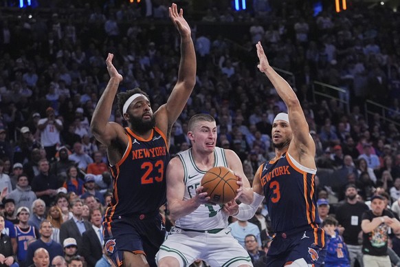 New York Knicks&#039; Mitchell Robinson (23) and Josh Hart (3) defend Boston Celtics&#039; Payton Pritchard (11) during the second half of Game 4 in the Eastern Conference semifinals of the NBA basket ...