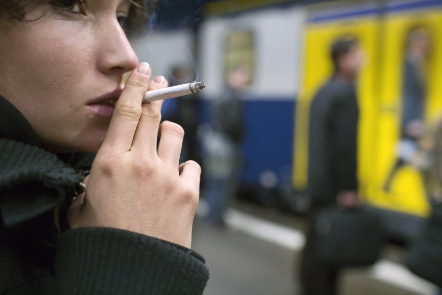Eine junge Frau raucht auf einem Bahnsteig im Bahnhof Winterthur eine Zigarette, waehrend sie auf ihren Zug wartet, aufgenommen am 9. November 2005. (KEYSTONE/Martin Ruetschi)