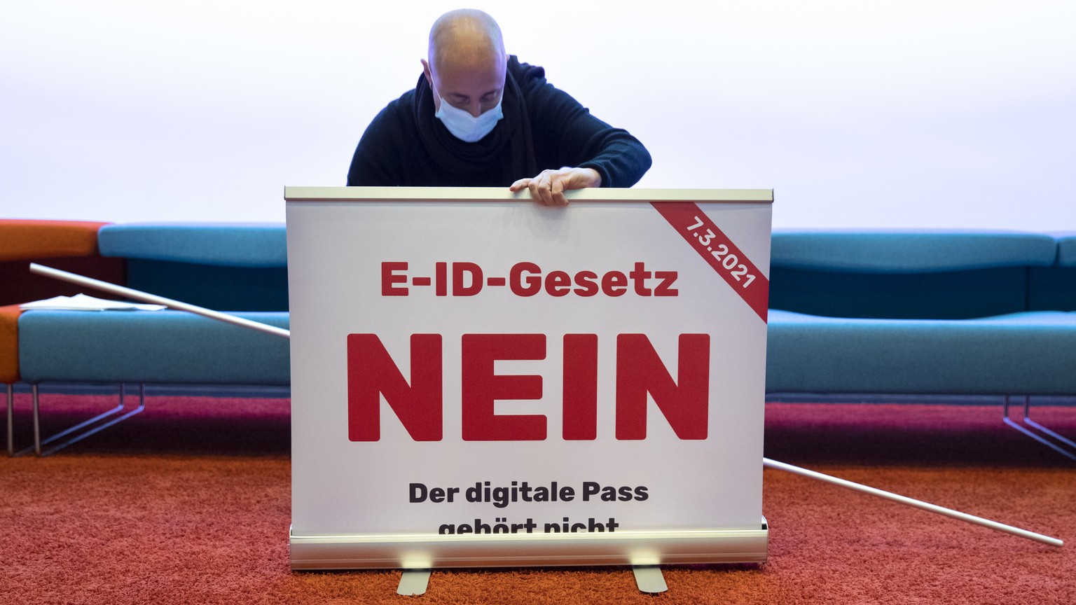 Ein Mitglied des Komitees stellt ein Plakat mit der Aufschritt &quot;E-ID-Gesetz NEIN&quot; auf, vor Beginn einer Medienkonferenz des Komitees fuer ein NEIN zum E-ID Gesetz, am Montag, 14. Dezember 20 ...