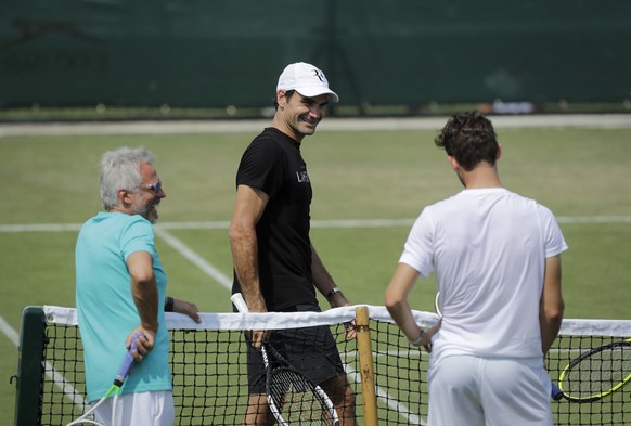 Roger Federer of Switzerland jokes during a practice session with Dominic Thiem, right, ahead of the start of the Wimbledon Tennis Championships in London, Sunday, July 1, 2018. The Championships will ...