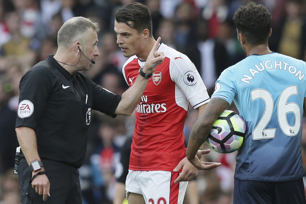 Arsenal's Granit Xhaka, center, is sent off by referee Jon Moss for a tackle on Swansea's Modou Barrow during the English Premier League soccer match between Arsenal and Swansea City at The  ...