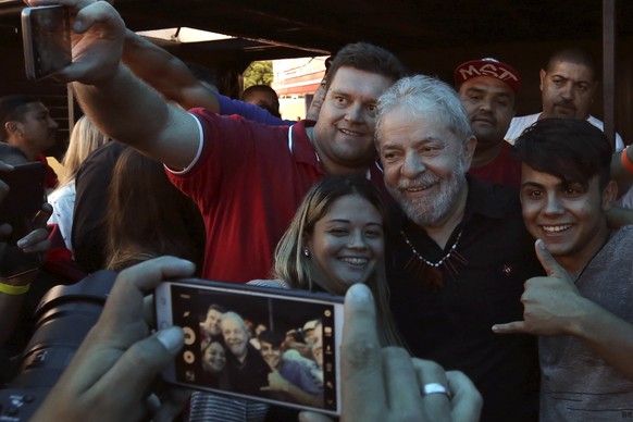 Brazil&#039;s former President Luiz Inacio Lula da Silva, center, takes photos with supporters at the end of a rally in Quedas do Iguacu, Parana state, Brazil, Tuesday, March 27, 2018. Despite his leg ...