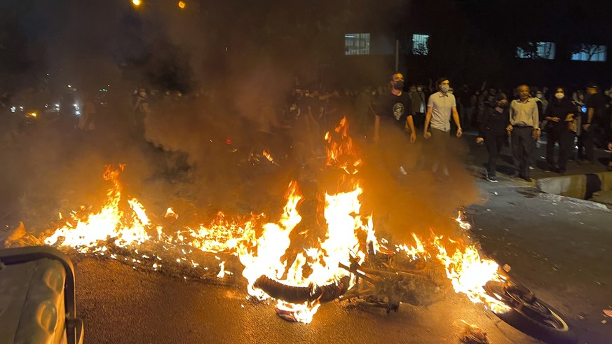 In this Monday, Sept. 19, 2022, photo taken by an individual not employed by the Associated Press and obtained by the AP outside Iran, a police motorcycle burns during a protest over the death of a yo ...