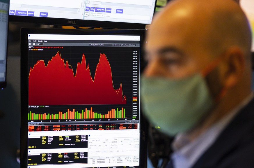 epa09693402 A trader works with a graph of Microsoft?s share price in the background on the floor of the New York Stock Exchange at the Opening Bell in New York, New York, USA, on 18 January 2022. The ...