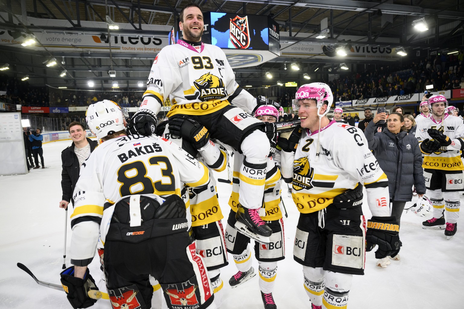 Le defenseur jurassien Jordane Hauert, 93, est porte en triomphe par ses coequipiers pour feter son dernier match et le maintien en National League, gauche, lutte pour le puck avec $, droite, lors du  ...